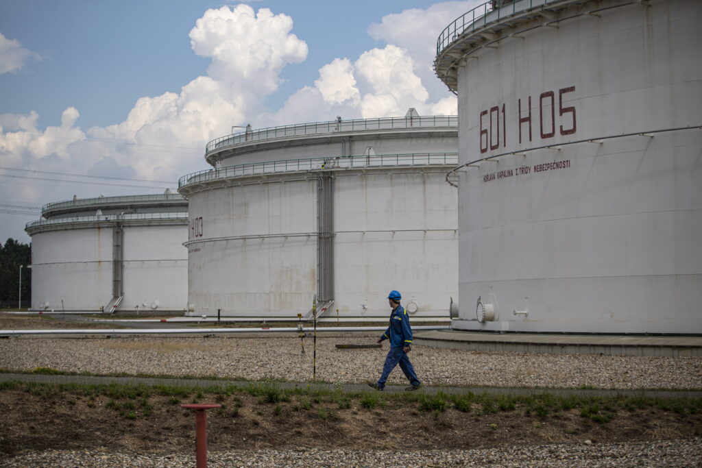 An employee walks past storage tanks at the Central oil tank farm operated by Mero CR near Nelahozeves, Czech Republic, 15 August 2022. Mero CR owns and operates the Czech part of the Druzhba pipeline and the IKL pipeline, is the sole transporter of crude oil to the Czech Republic, and also provides storage for the Czech emergency strategic oil reserves. Both pipelines enter the Central oil tank farm near Nelahozeves, where the company has built a total of 17 oil tanks with a total storage capacity of 1 675 000 m3. In June 2022, the European Union approved a sixth package of sanctions over Russia